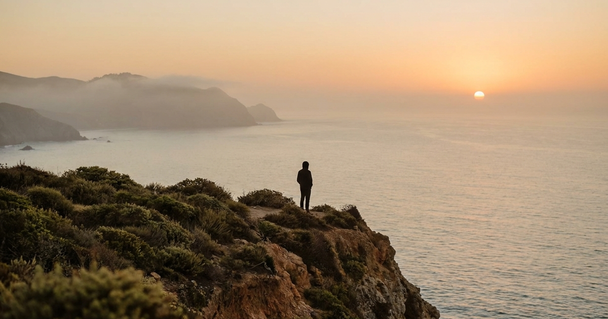 Person reflecting on grief and Crohn's disease while looking at a quiet landscape